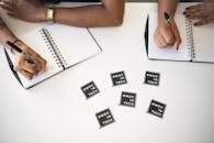 几位女性在技术会议上合作，在白色桌面的笔记本上做笔记