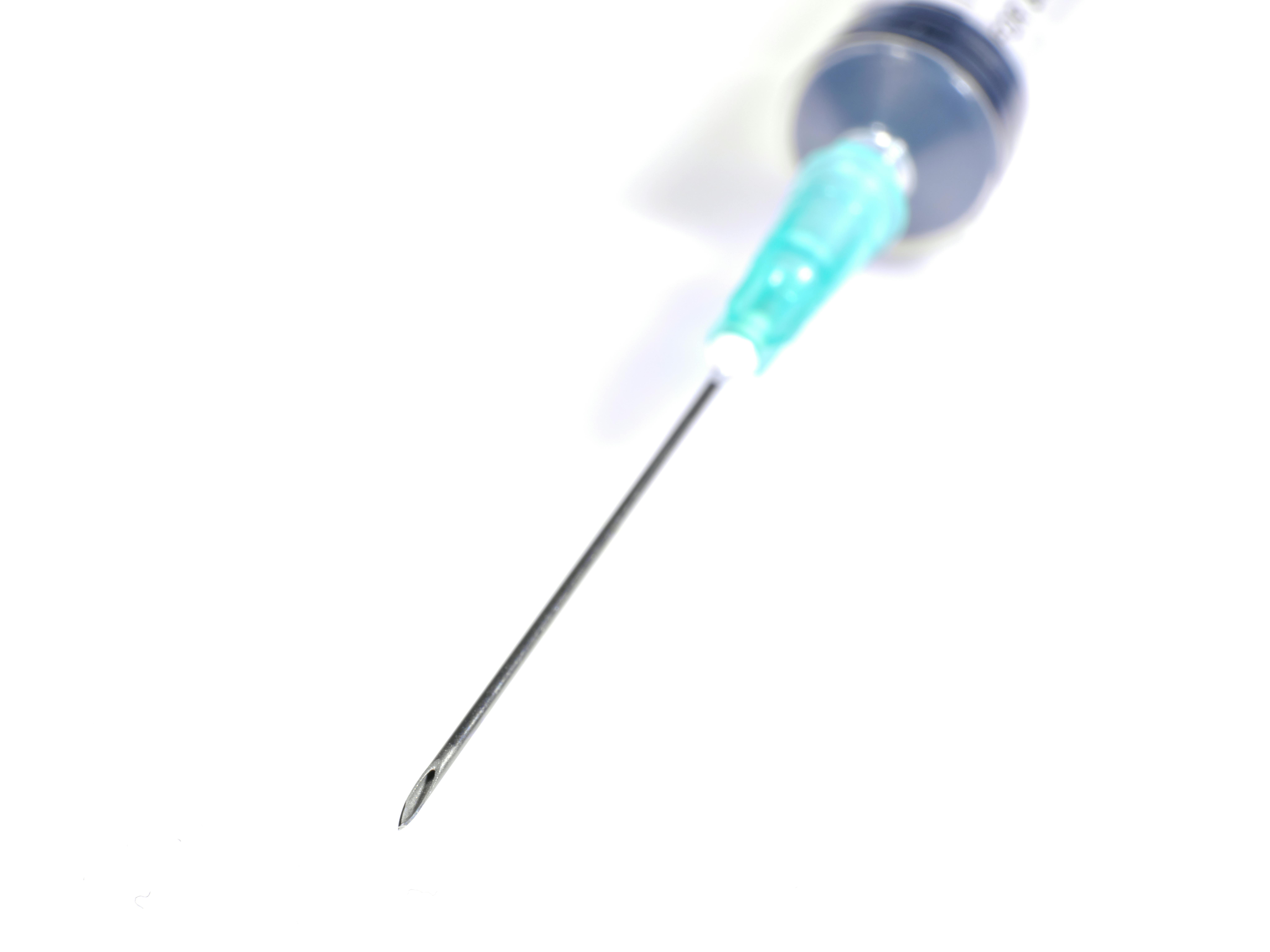Macro shot of a medical syringe needle on a white background, ideal for healthcare themes.
