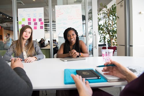 Free Two Women Sitting in Front of White Table Stock Photo