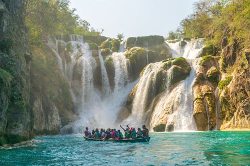 People on Boat near Majestic Waterfall