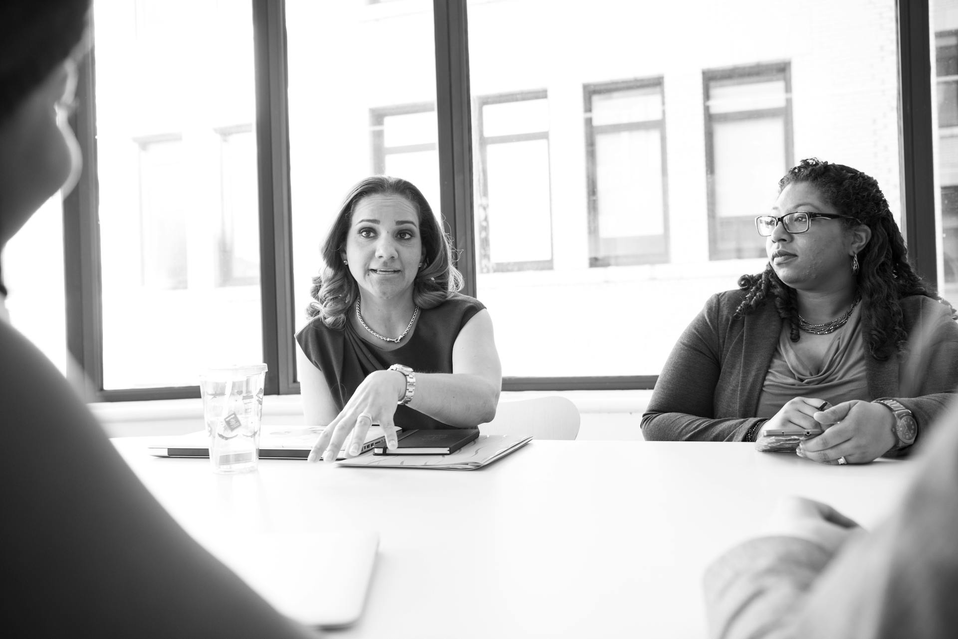 A diverse group of women engaging in a professional business meeting in a modern office setting.