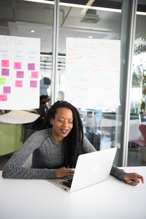 Woman in Gray Sweater Sitting in Front of Laptop Computer on Table