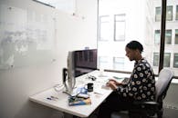 一位女士坐在现代办公室的办公桌前，用台式计算机工作