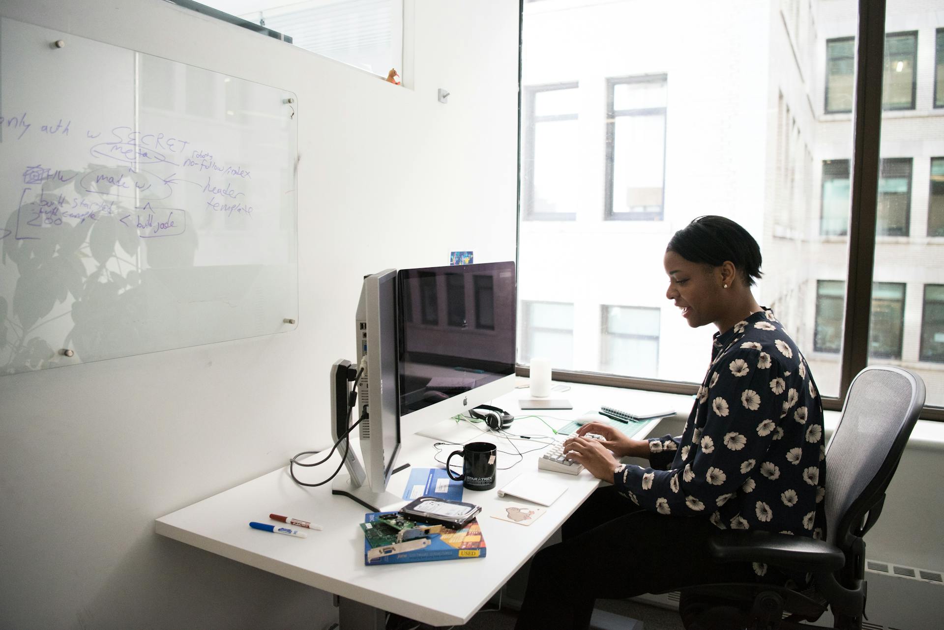 Woman sitting at a desk in a modern office, working on a desktop computer.