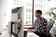 在现代办公室里，职业女性正在打字，办公室有大窗户和室内植物