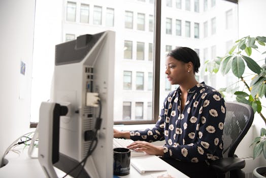 在现代办公室里，职业女性正在打字，办公室有大窗户和室内植物