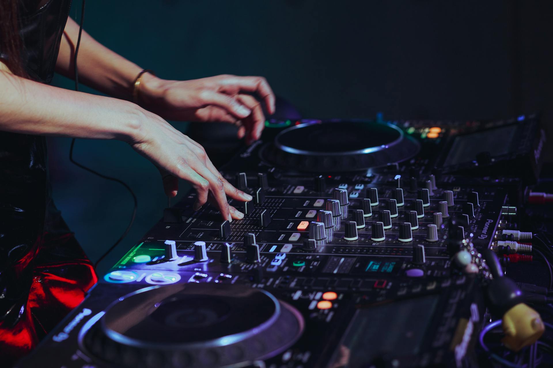 A female DJ skillfully mixing music on a professional DJ console at a lively Bangkok nightclub.