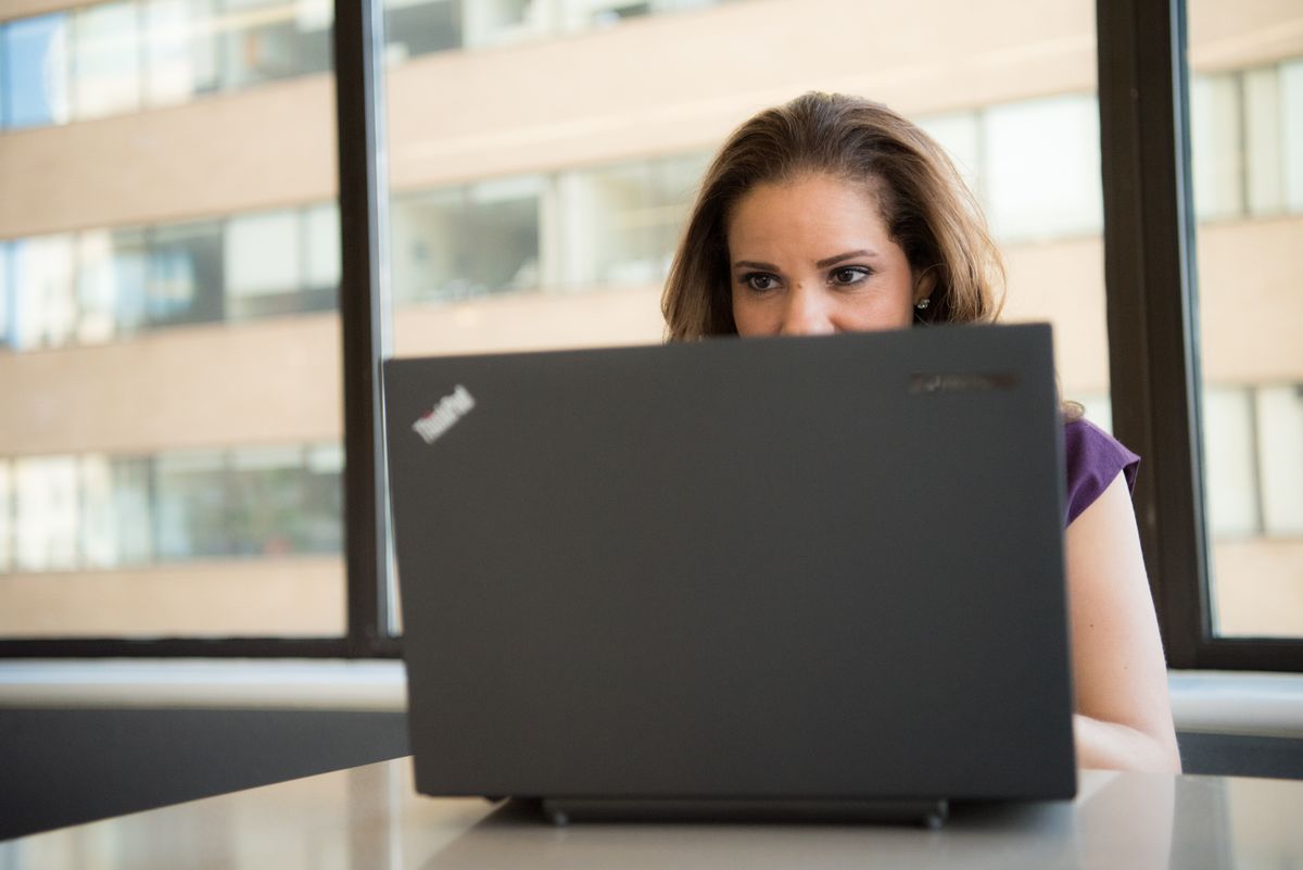 A focused woman editing presentation slides on a laptop in a bright modern office