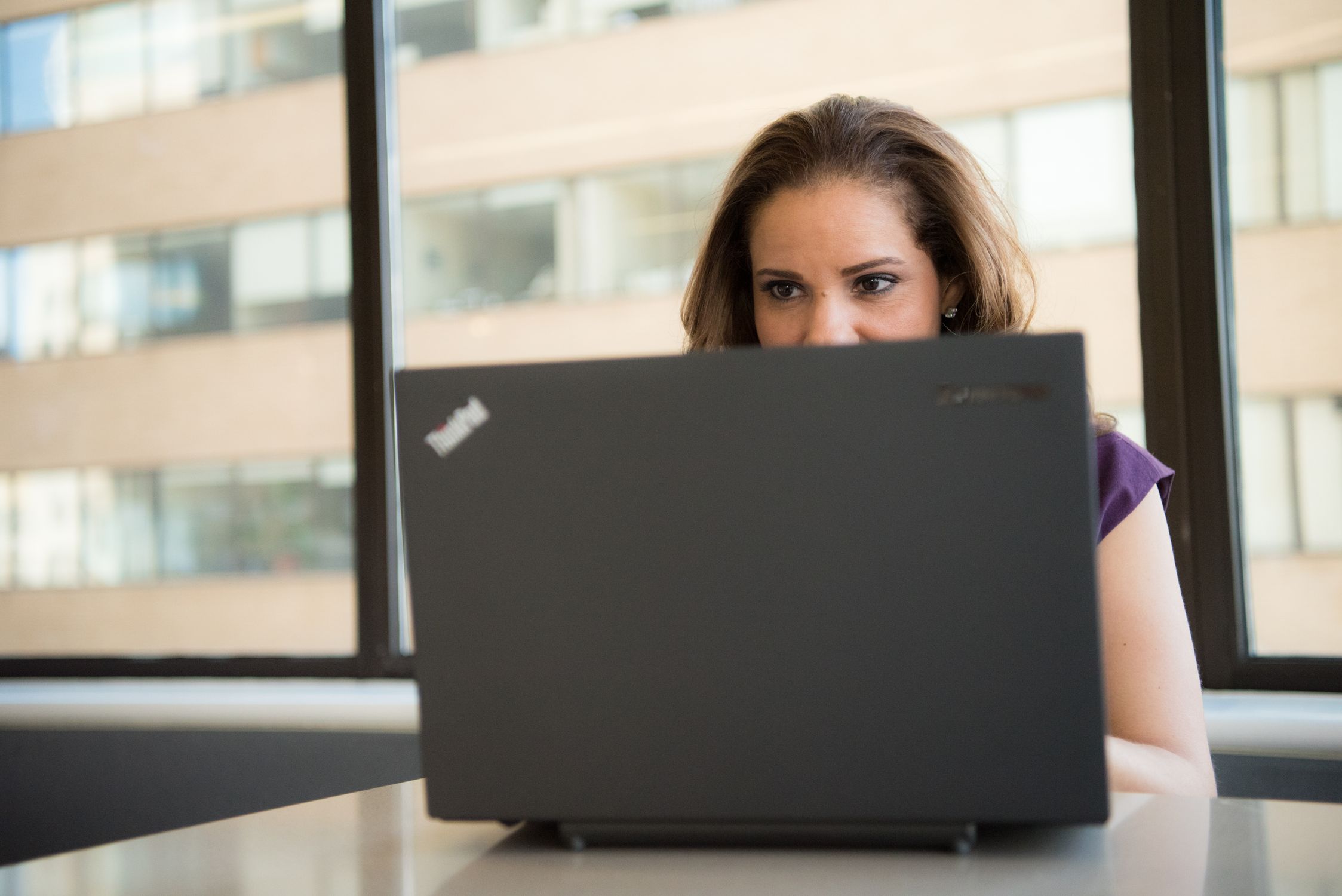 Mulher demonstrando frustração e sobrecarga trabalhando no computador, refletindo a pressão por produtividade e exaustão mental.