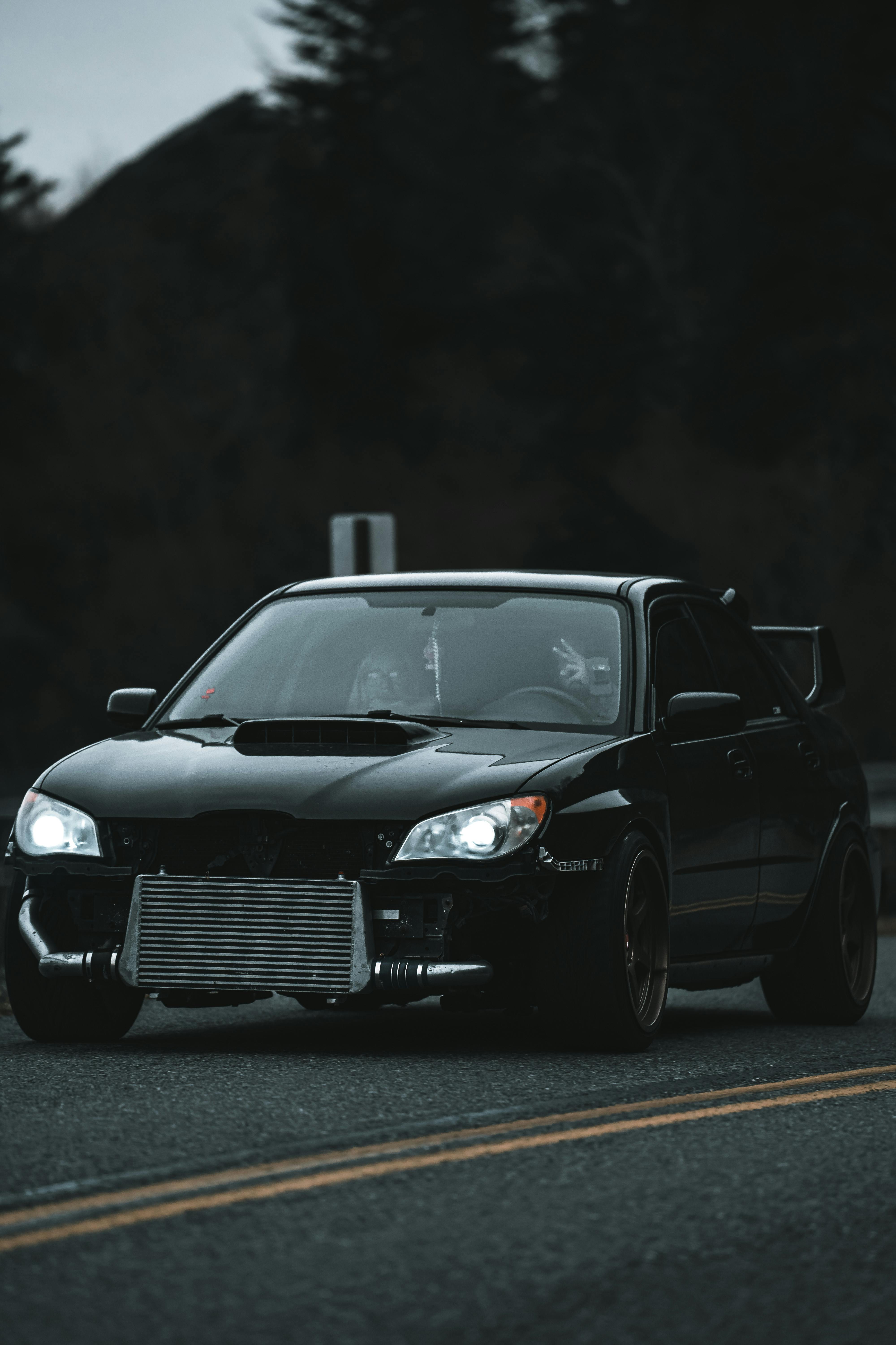 Free A sleek black sports car captured on an asphalt road, perfect for automotive enthusiasts. Stock Photo