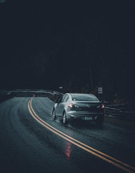 A car on a dark, wet road, creating a moody and dramatic scene.