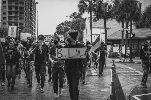 Free Demonstrators wearing masks march through city streets in Black Lives Matter protest, holding signs and banners. Stock Photo
