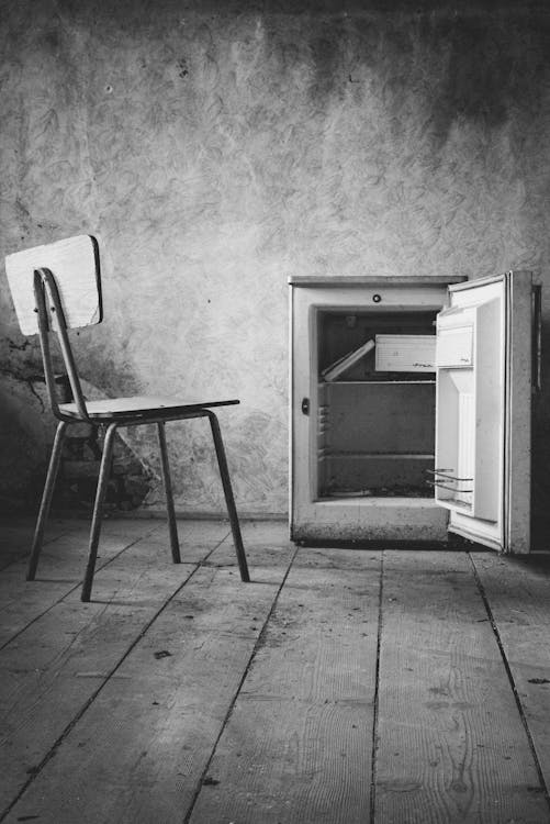 Free Chair and a Small Fridge in an Empty Abandoned Room  Stock Photo