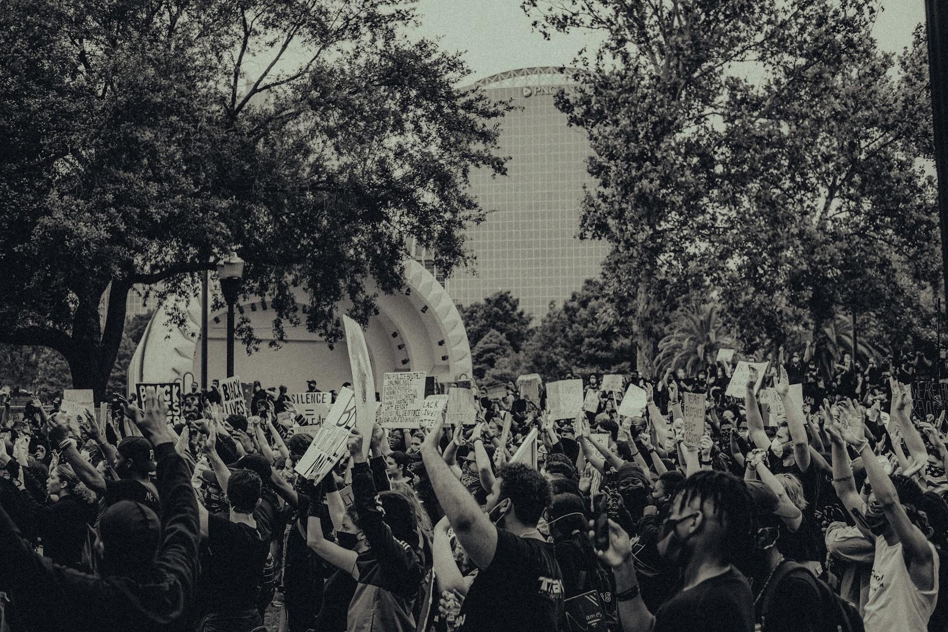 A large crowd of activists raising hands and placards during a Black Lives Matter protest outdoors.