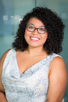 一位戴着眼镜、面带微笑的时髦女性，在室内环境中散发着自信