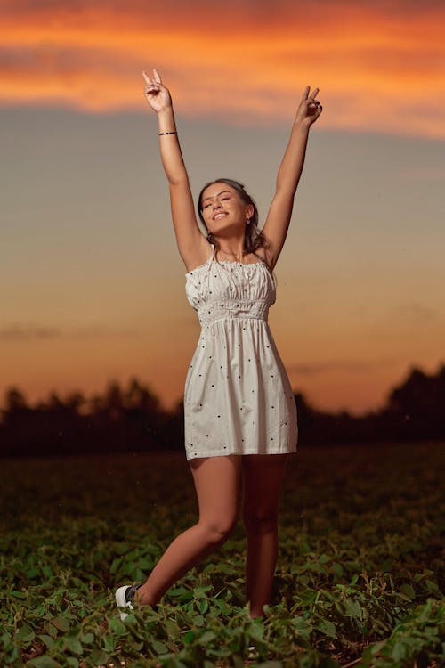 Free Beautiful Woman Raising Her Hands and Doing a Peace Sign Stock Photo