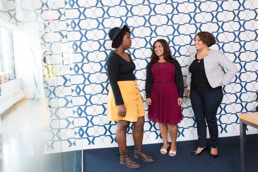 Group of women chatting in a stylish office with geometric patterns. Perfect for lifestyle and fashion themes.