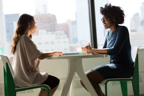 Twee Vrouwen Zitten Op Stoelen Naast Raam