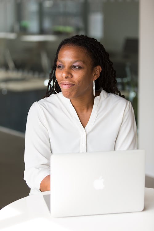 Woman Wearing White Button-up Shirt Sitting in Front of Table