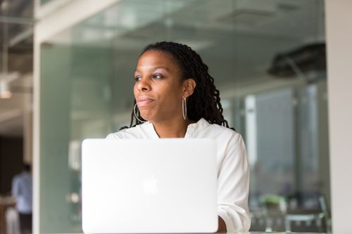 Free A professional black woman concentrating on work using a laptop in a modern office setting. Stock Photo