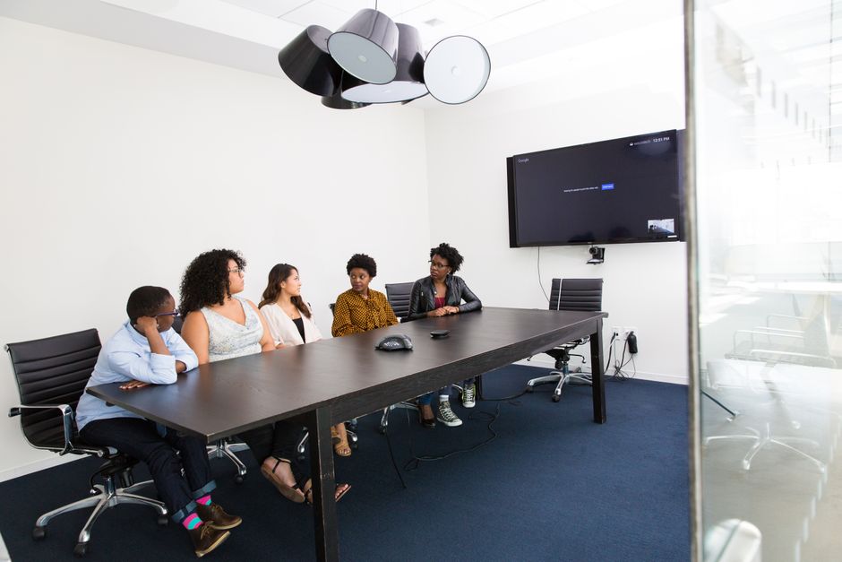 Group of diverse professionals engaged in a meeting in a modern office setting with technology integration.