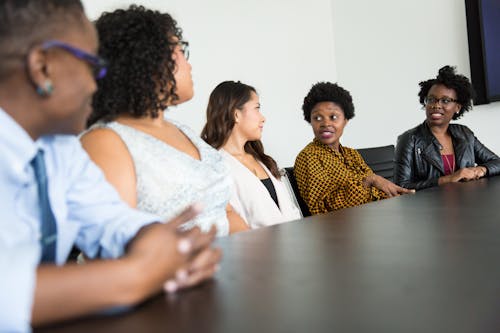 Free Four Women and One Man Sitting Near Table Inside Room Stock Photo