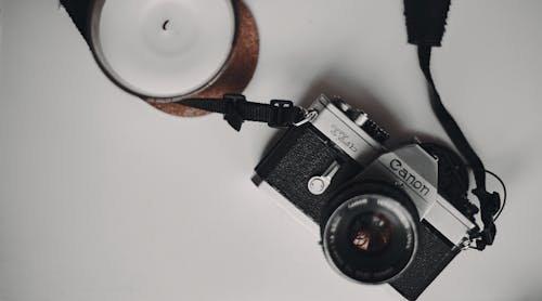 Free Black and Silver Canon TLb Camera beside a Candle Stock Photo
