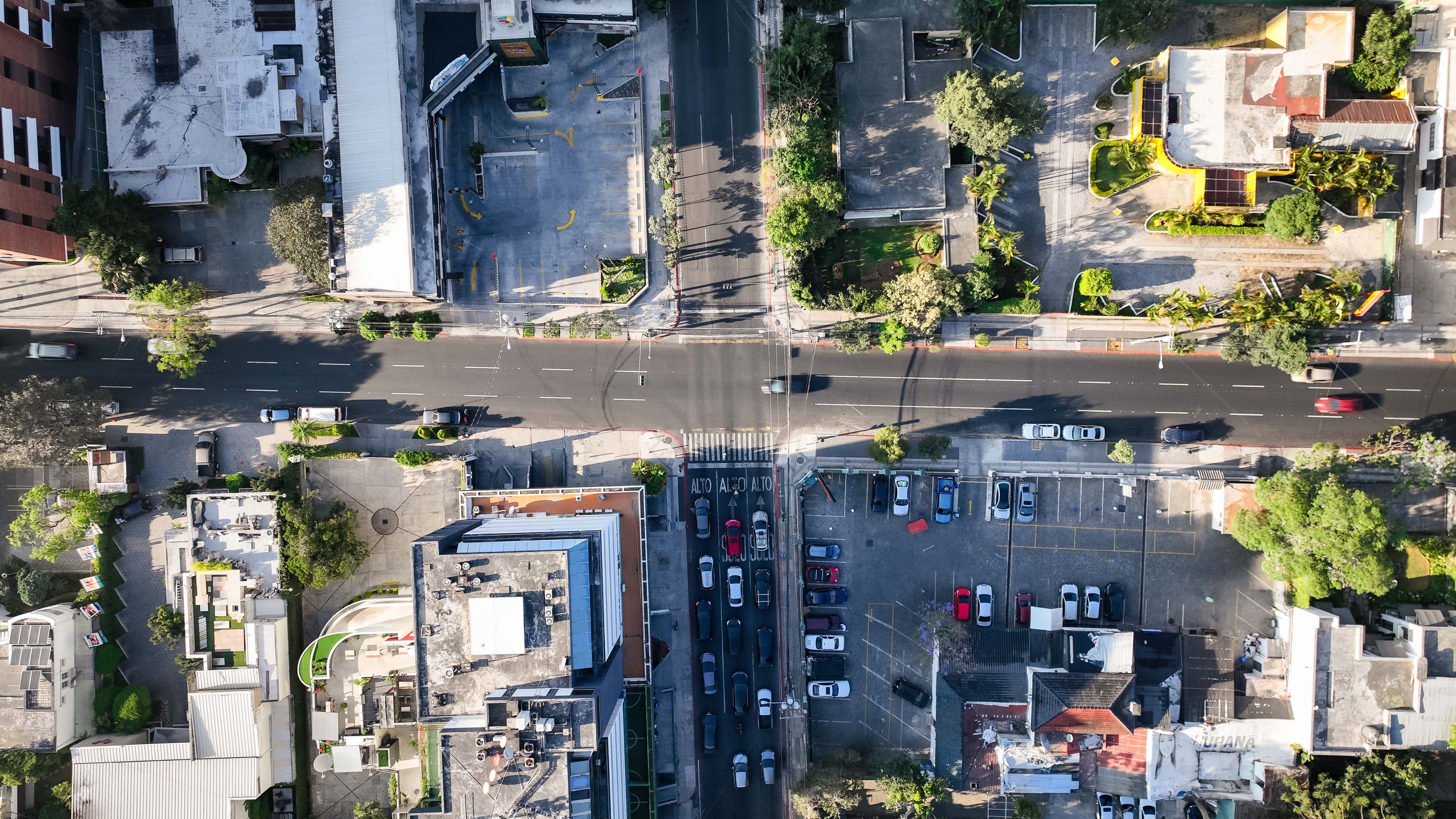 Top-down view of a busy city intersection with visible cars, roads, and buildings.