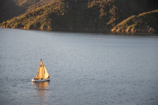 日落时分，一艘帆船滑行在宁静的湖面上，山丘郁郁葱葱