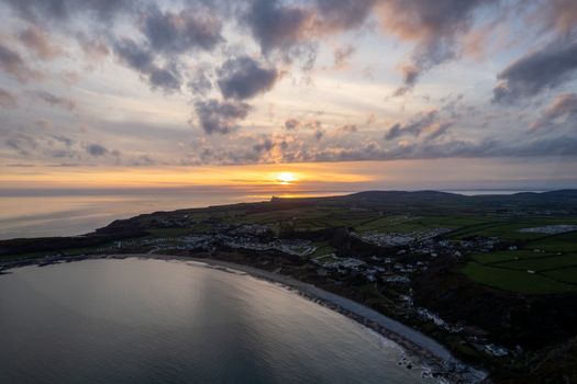 Beautiful aerial view of Slade coastline in Wales, UK, with stunning sunset colors over the sea.