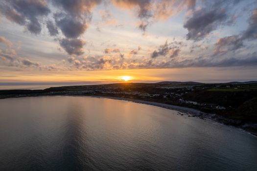 A breathtaking aerial view of a sunset over Slade's coastline in Wales, showcasing serene waters and vibrant skies.