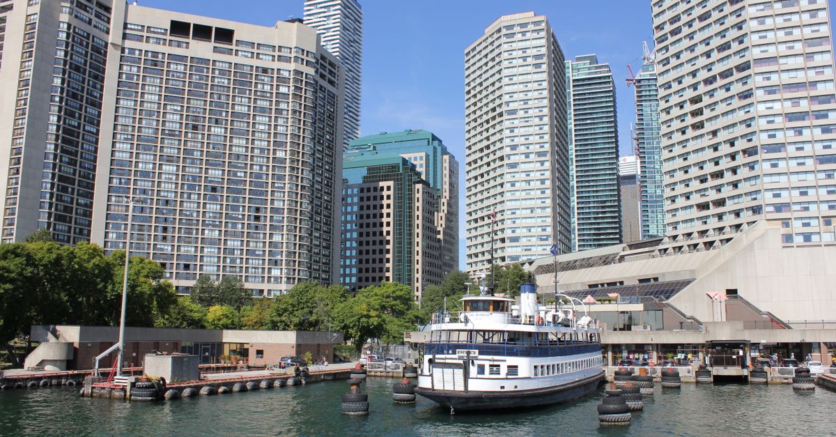 A scenic urban skyline with a docked ferry boat against a clear blue sky.