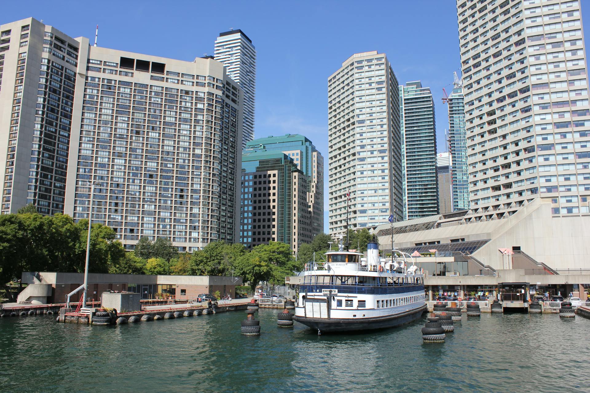 A scenic urban skyline with a docked ferry boat against a clear blue sky.