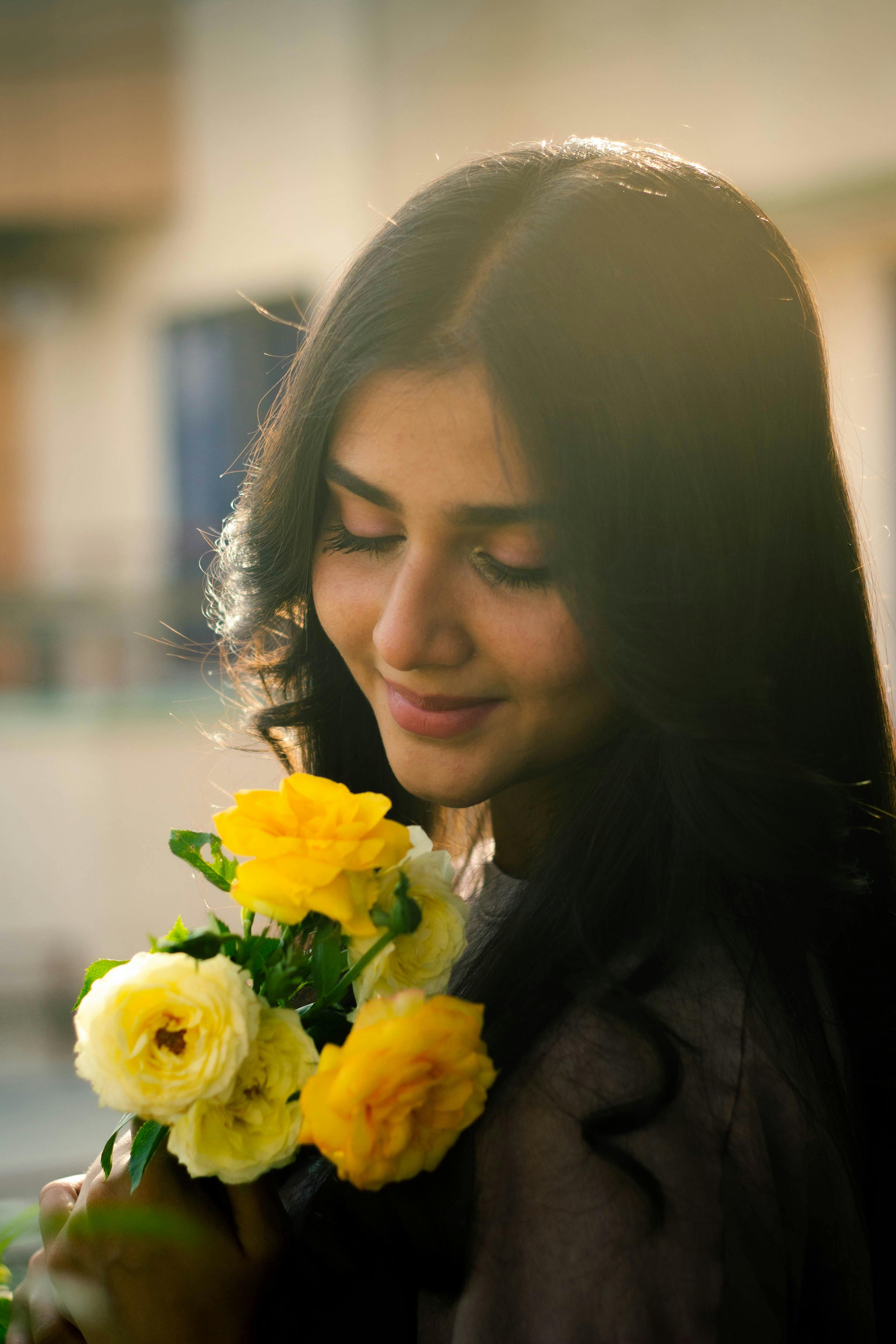 A woman smelling red flowers free stock photo