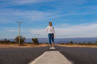 Woman in White and Blue Striped Long Sleeve Shirt and Blue Denim Jeans Standing on Gray
