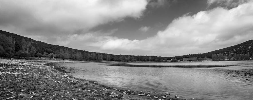 Stunning monochrome panorama of Ifran Lake, surrounded by hills and a cloudy sky.