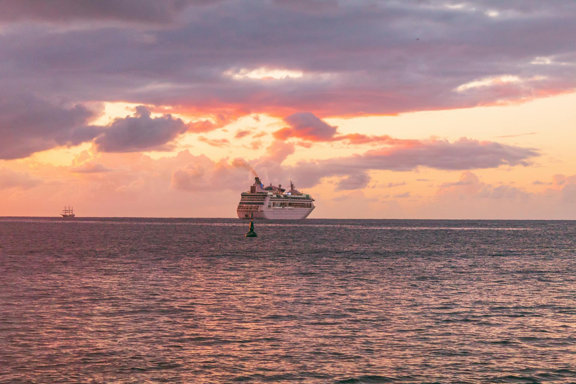 A cruise ship sails during a vibrant sunset over the Caribbean Sea near Grenada.