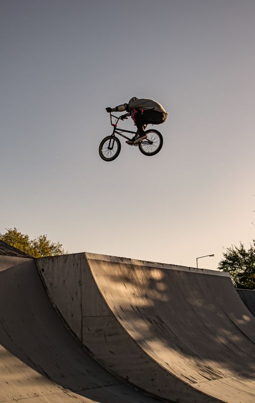 Free A skilled BMX rider performs a stunning high jump at an outdoor skate park under clear skies. Stock Photo