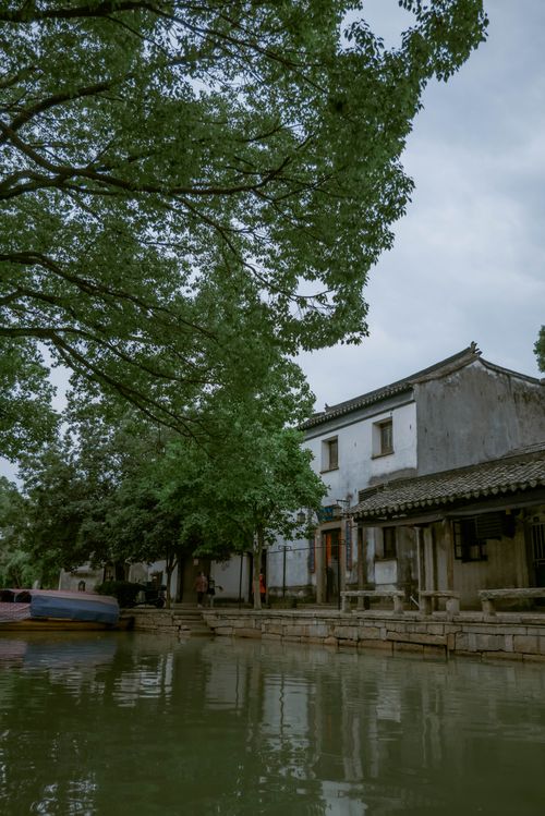 Free Peaceful scene of a canal with traditional houses and lush greenery in a quaint setting. Stock Photo