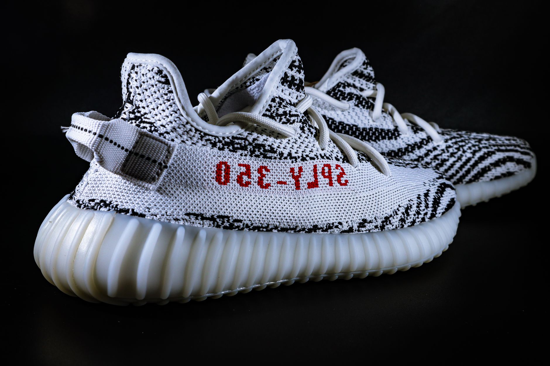 Close-up of Yeezy sneakers on a black background, showcasing detailed knit patterns.