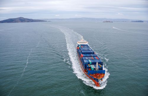 Free Aerial view of a large container ship sailing through open ocean waters. Stock Photo