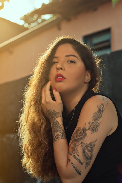 Free Portrait of a tattooed woman in a sleeveless top with natural sunlight. Stock Photo