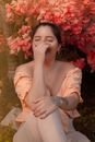 Woman in White Dress Sitting on Ground With Red Flowers