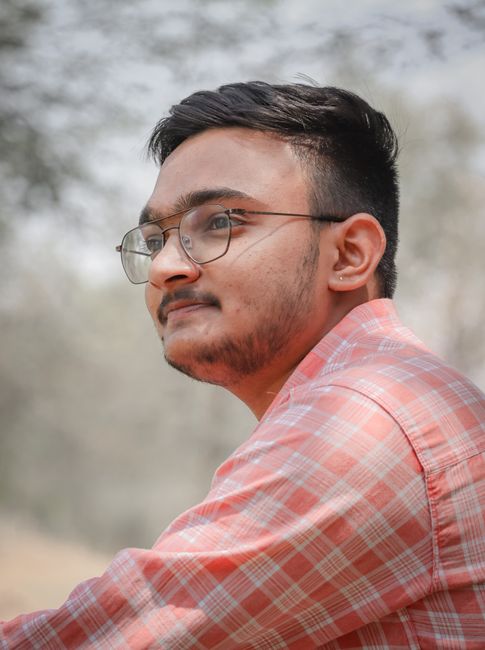 Portrait of a young bearded man wearing eyeglasses and a plaid shirt, enjoying the outdoors in India.
