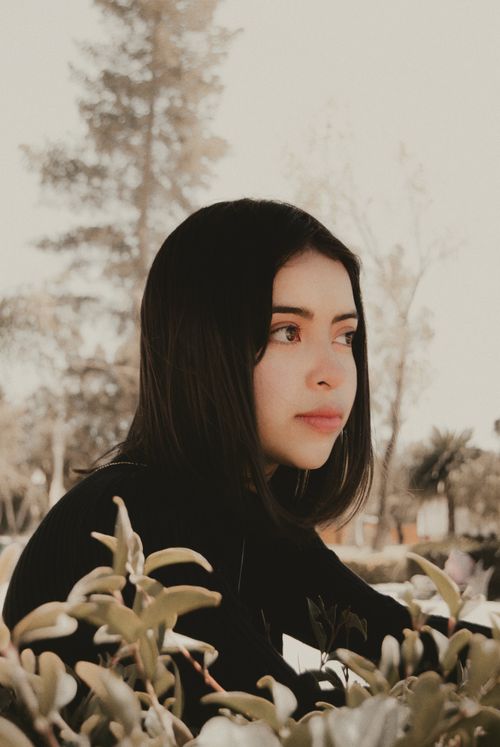 Free A young woman in black sweater gazes thoughtfully among greenery in Pachuca, Mexico. Stock Photo