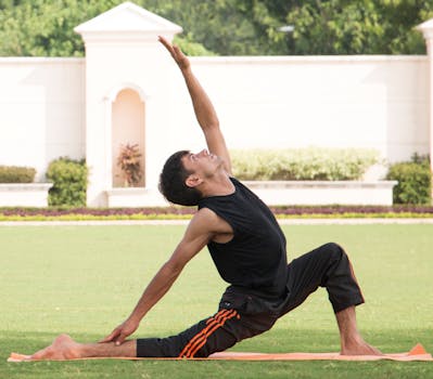 Adult male performing yoga crescent lunge pose outdoors on a sunny day.