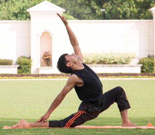 Free Adult male performing yoga crescent lunge pose outdoors on a sunny day. Stock Photo