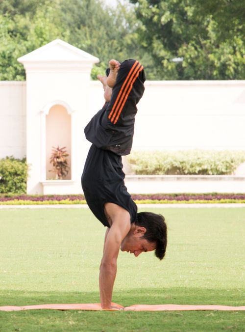 Free Man doing a handstand on a yoga mat in an outdoor park setting. Stock Photo