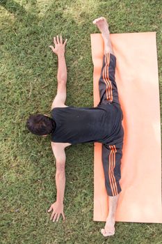 A man stretches on a yoga mat outdoors, captured from above. Perfect for fitness themes.