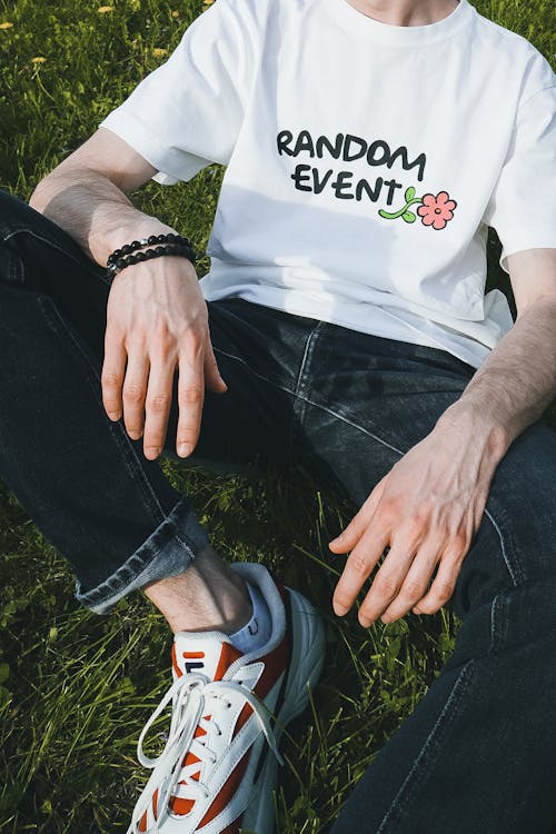 
A Man in a White Shirt and Denim Pants Sitting on the Grass